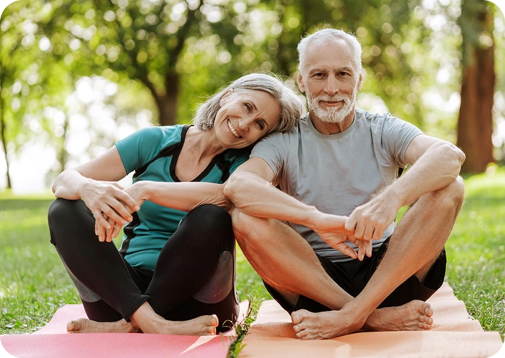 Happy senior couple sitting on yoga mats