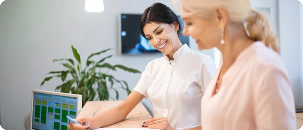 Receptionist assisting a client at a clinic desk